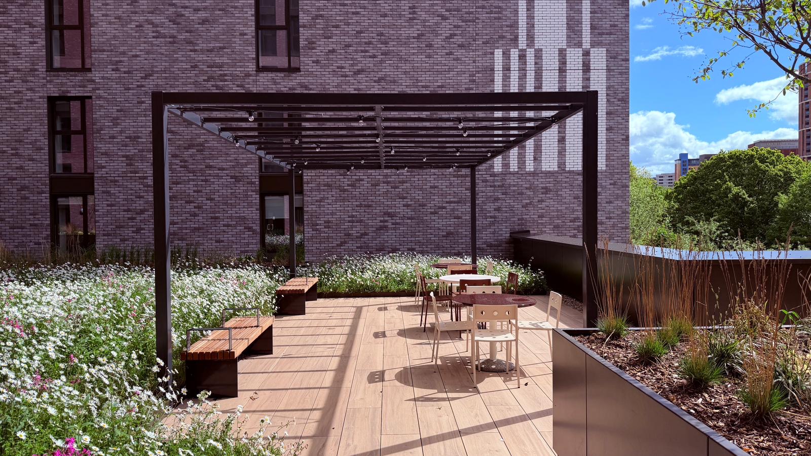 Steel pergola with festoon lighting, hardwood benches and wildflower planters. — comparable to schemes we deliver in Camden